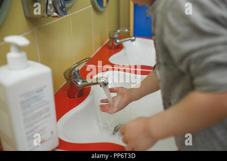 Bambino lavarsi le mani con sapone in bagno in una scuola materna. Foto Stock