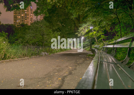 Un tratto deserta di camminamento e panchine vicino al laghetto sul lato sud di Central Park in una serata tranquilla nel centro cittadino di New York. Foto Stock