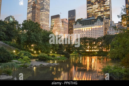 Le luci dello skyline di Manhattan sono riflesse su Central Park iconici stagno su una chiara e serata tranquilla. Foto Stock