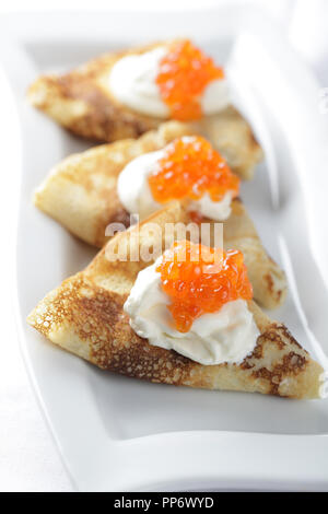 Blinis con panna acida e caviale rosso Foto Stock