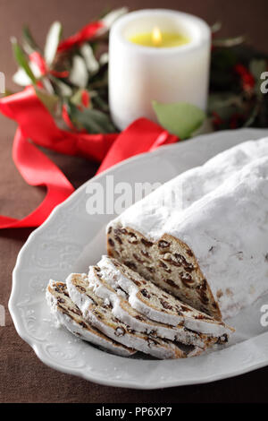 Il Natale lo Stollen con uvetta contro la ghirlanda di Natale e candela Foto Stock