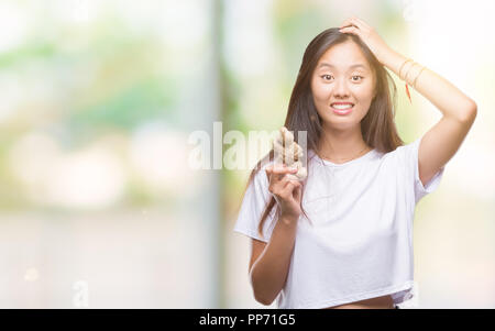 Giovane donna asiatica azienda organico fresco su sfondo isolato ha sottolineato con la mano sulla testa, sconvolto con vergogna e la sorpresa di fronte, arrabbiato e vanificare Foto Stock