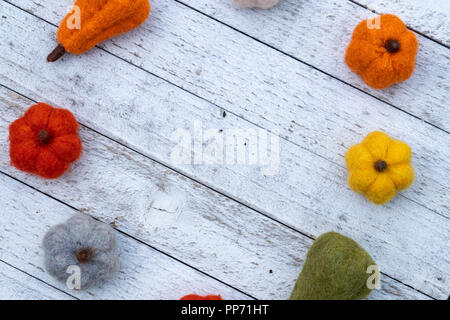 Lay piatto autunno sfondo con feltro zucche fuzzy e zucche su un bianco sullo sfondo di legno. Concetto di caduta con spazio di copia Foto Stock