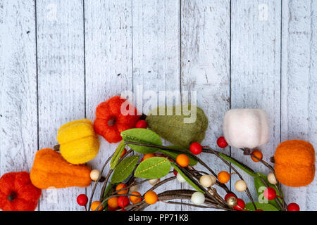 Lay piatto autunno sfondo con feltro zucche fuzzy e zucche su un bianco sullo sfondo di legno. Concetto di caduta con spazio di copia Foto Stock