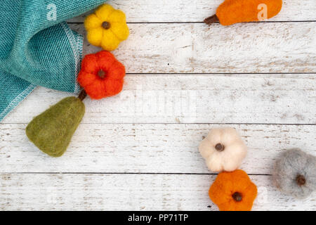 Lay piatto autunno sfondo con feltro zucche fuzzy e zucche su un bianco sullo sfondo di legno. Concetto di caduta con spazio di copia Foto Stock