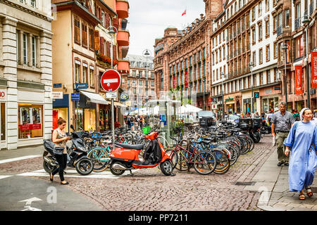 Centinaia di biciclette e scooter parcheggiato alla fine di Rue de Vingt-Deux Novembre, Strabourg, Francia con una suora nel suo abito passeggiando dalla. Foto Stock