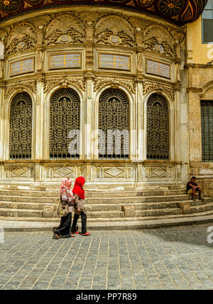 Due donne musulmane a piedi passato il delicato facciata arrotondata del Sabil-Kuttab Isma'll Pasha in Cairo Islamico. Foto Stock