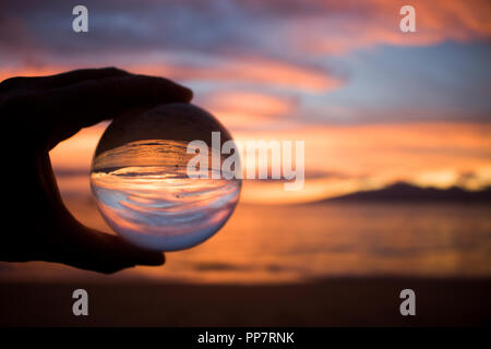 Arancione tramonto con luce riflettendo sulla superficie dell'Oceano catturati nella sfera di vetro Foto Stock