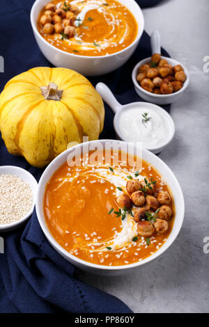 Carote zuppa di zucca con il piccante di ceci e i semi di sesamo sulla pietra grigia sfondo spazio di copia Foto Stock
