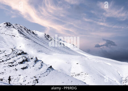 Incantevole paesaggio invernale con montagne coperte di neve al tramonto. Foto Stock