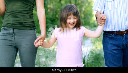 Bellissima bambina con la sindrome di down a piedi con i genitori Foto Stock