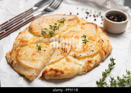 Pizza con pera e formaggio blu guarnito con timo fresco e pepe. Primo piano. Mini pizza pizza di piccole dimensioni Foto Stock