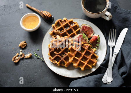 Tutto il frumento cialde con il miele e la tazza di caffè nero su sfondo di calcestruzzo. Una gustosa prima colazione Foto Stock