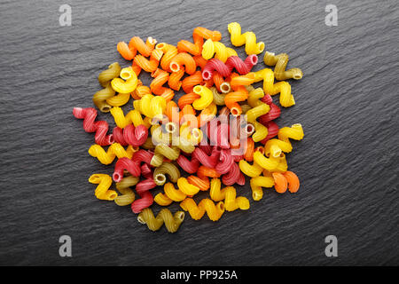 Pasta multicolore è sparso su un nero ardesia sfondo. luogo per il testo Foto Stock