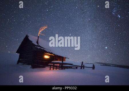 La notte con le stelle. Paesaggio Di Natale. Casa in legno nel villaggio di montagna Foto Stock