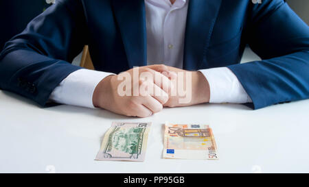 Primo piano immagine dell uomo d affari dubitare tra investimenti in euro o dollari denaro Foto Stock