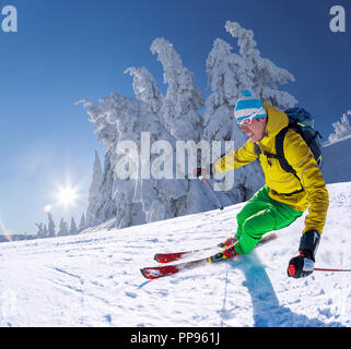 Sciatore in discesa sugli sci in alta montagna contro il cielo blu Foto Stock