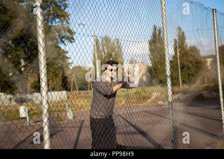 Il ragazzo in occhiali da sole tenendo la maglia di ferro sul parco giochi Foto Stock