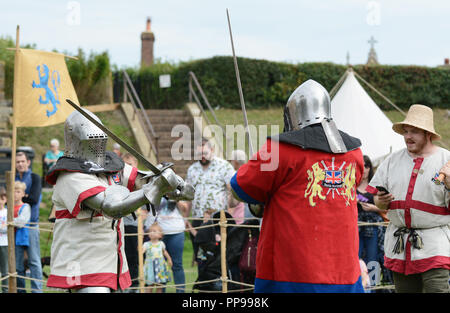 TONBRIDGE, Inghilterra - 9 Settembre 2018: spada lotta tra due combattenti di combattimento vestito in armatura medievale; un marshall in un St Georges Cross ti tabard Foto Stock