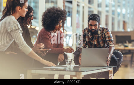 I partner aziendali in una riunione per discutere idee seduto in ufficio. Imprenditore lavora su laptop seduta femmina con i colleghi in ufficio. Foto Stock