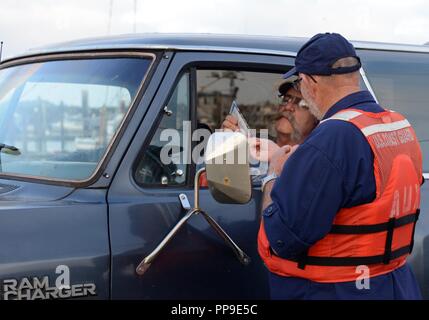 Un Coast Guard organo ausiliario passa fuori la nautica informazioni di sicurezza per un diportista più preparando a lanciare il suo personale nave da pesca al lancio in barca nel porto di Chinook, nello Stato di Washington, 17 ago 2018. Durante l annuale Coho salmon run vi è un innalzamento netto in ricreativo ai barcaioli di Columbia River e la protezione di litorale passi fino la sua postura per garantire sicurezza alle imbarcazioni. Foto Stock