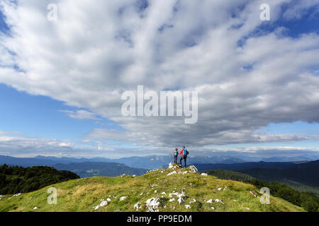 La madre e il figlio in piedi sulla parte superiore di erba di montagna rivestita, ammirando una splendida vista, Mozic, Slovenia Foto Stock