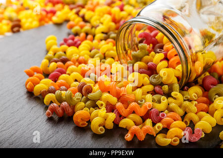 Pasta multicolore è sparso su un nero ardesia sfondo. luogo per il testo Foto Stock