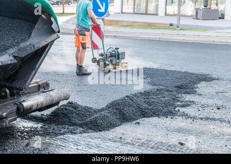 I lavoratori stradali compact l'asfalto con una vibrante rammer sulla strada, Germania Foto Stock