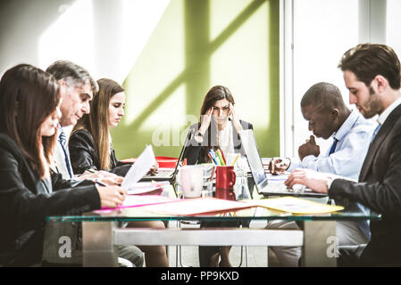 Imprenditrice avente mal di testa durante una riunione di lavoro - persona depressa con problemi finanziari Foto Stock