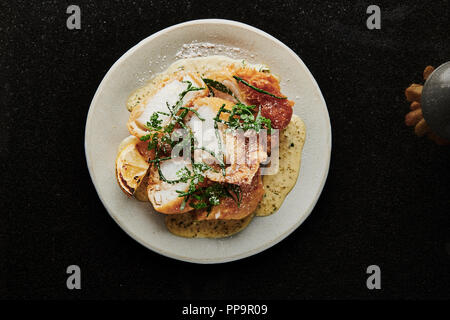 Delizioso merluzzo croccante su piatto bianco con patatine fritte in una ciotola con aceto di malto in polvere nel fresco ristorante londinese del tooting Market fish and chips Foto Stock