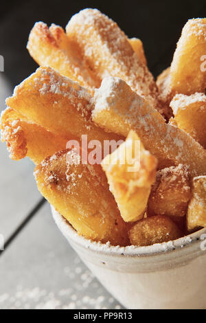 Delizioso merluzzo croccante su piatto bianco con patatine fritte in una ciotola con aceto di malto in polvere nel fresco ristorante londinese del tooting Market fish and chips Foto Stock