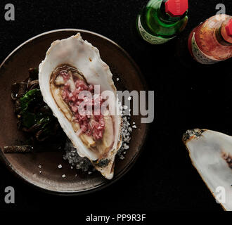 Classica ostrica sana fresca di mare con salsa tabasco di scalogni tritata nel guscio del fresco ristorante londinese di tooting Market afrodisiaco Foto Stock