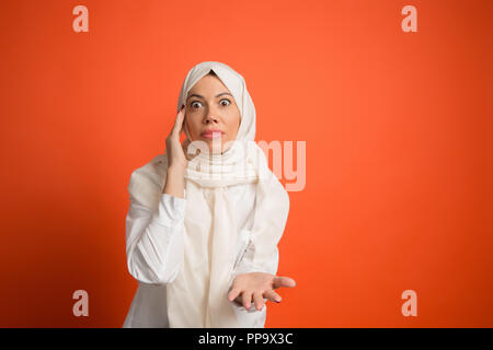 Sostengono, adducendo il concetto.La donna araba in hijab. Ritratto di una ragazza, ponendo a. rosso di sfondo per studio. Giovane donna emotiva. Le emozioni umane, espressione facciale concetto. Vista frontale. Foto Stock