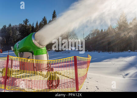 Lavorando neve pistola sul fianco di una collina nella località Foto Stock