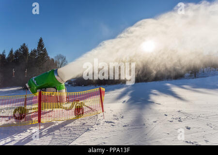 Lavorando neve pistola sul fianco di una collina nella località Foto Stock
