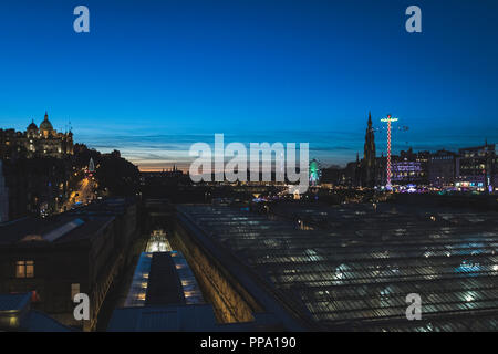 Il Castello di Edimburgo e il Mercato di Natale al crepuscolo con vista sulla stazione ferroviaria Foto Stock
