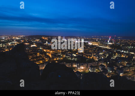 Edinburgh City skyline notturno con Salisbury Crags in primo piano, Scozia Foto Stock