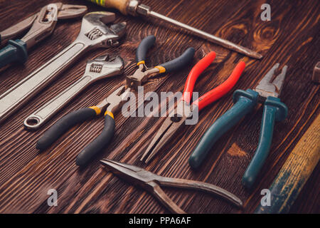 Diversi strumenti di lavoro su un tavolo di legno - un martello, tronchesi, pinze, scalpelli e delle chiavi Foto Stock