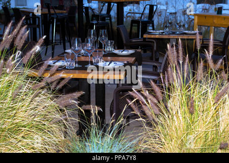 Serviti di un tavolo da pranzo con piatti e bicchieri di cristallo, sotto una tettoia in un ristorante all'aperto. Lo spagnolo beach resort Blanes in estate. In Costa Brava Catalogna Foto Stock