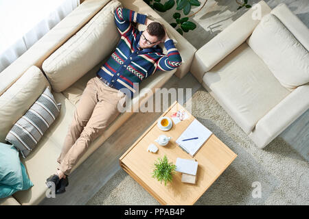 Vista sopra ritratto di pensieroso psicologo maschio rilassante dopo la sessione mentre sdraiato sul lettino in ufficio soleggiato, spazio di copia Foto Stock