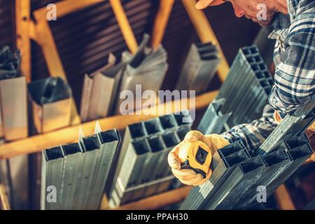 Metallo telai di muretti a secco su rack all'interno di edificio Forniture Store. Imprenditore caucasico cercando materiali di destra. Foto Stock