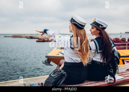 Due college studenti donne di Marine Academy a piedi dal mare indossando uniforme. Amici punta in distanza sul molo. La flotta navale di Ucraina Foto Stock