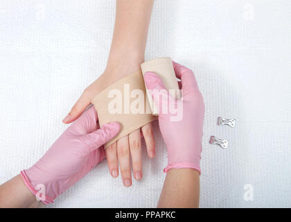 Giovani mani femminili indossando guanti di rosa involucro elastico bendaggio ace sul giovane mano e polso. Trattamento medico. Foto Stock