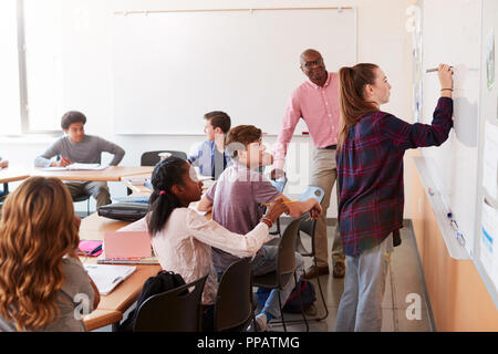 Femmina di alta scuola allievo scrivere sulla lavagna in classe Foto Stock