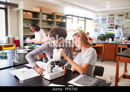 Alta scuola gli studenti guardando attraverso il microscopio nella classe di biologia Foto Stock