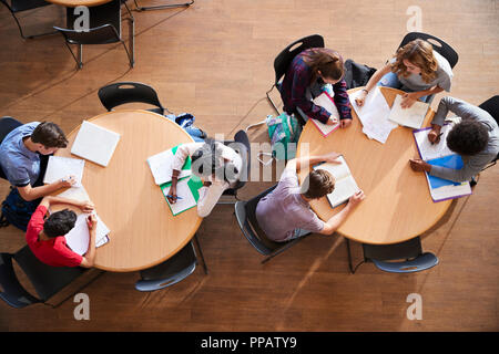 Colpo di overhead di alta scuola gli studenti in gruppi di studio intorno a tavoli Foto Stock