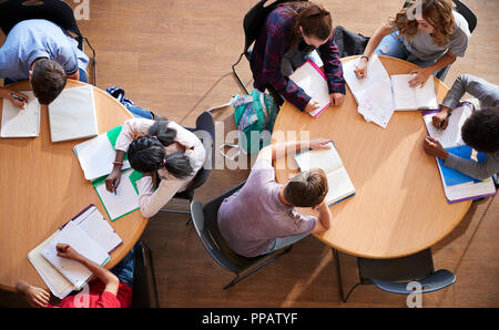 Colpo di overhead di alta scuola gli studenti in gruppi di studio intorno a tavoli Foto Stock