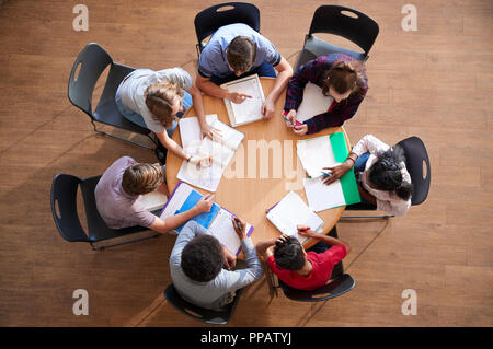 Colpo di overhead di alta scuola gli studenti in gruppi di studio intorno a tavoli Foto Stock