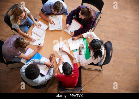 Colpo di overhead di alta scuola gli studenti in gruppi di studio intorno a tavoli Foto Stock