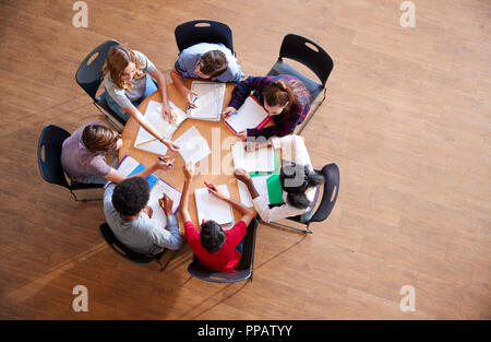 Colpo di overhead di alta scuola gli studenti in gruppi di studio intorno a tavoli Foto Stock